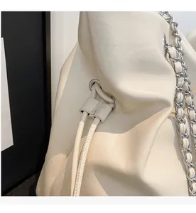Detail of the drawstring closure and silver chain strap on a cream leather bucket bag
