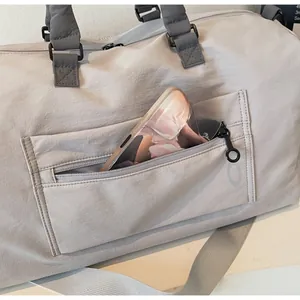 Detail of the outer zipper pocket on a light grey travel bag with a phone inside