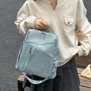 Detail of light blue embossed checkered backpack with woven strap and silver zippers