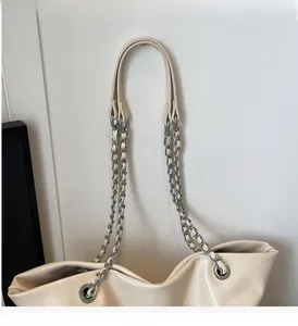 Detailed close-up of beige leather tote strap with silver metal chain and grommets
