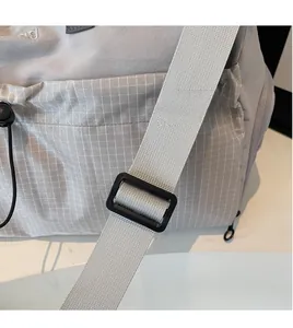 Close-up of adjustable woven shoulder strap and grey plaid fabric on travel duffle bag
