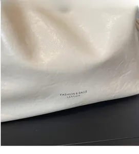 Close-up of white pleated leather tote with vintage chain and fashion logo print