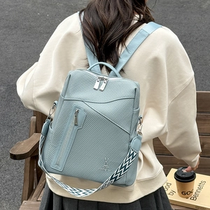 Macro shot of light blue PU leather backpack showing cross-grain texture and wide strap