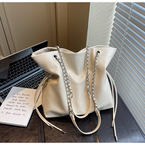 Close-up of beige tote bag showing drawstring closure and silver chain shoulder strap
