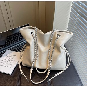 Detailed close-up of cream-white tote bag featuring drawstring closure and silver chain strap