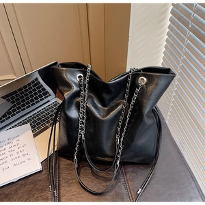 Detail of black faux leather tote with silver chain strap and drawstring design