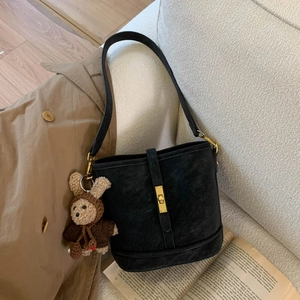 Detail of black matte bucket bag featuring a golden twist lock and a cute bear charm
