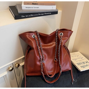Detailed view of caramel leather tote with chain strap and side drawstring accents
