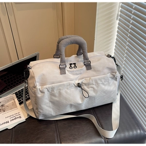 Detail of light grey travel bag showing quilted handle and woven front pocket design