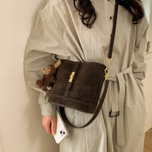 Detail of vintage dark brown bucket bag with matte texture and decorative gold buckle