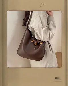Detail of dark brown faux leather bucket bag with a cute sausage dog pendant