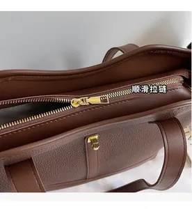 Detail of smooth gold zipper and pebble leather texture on a brown tote bag