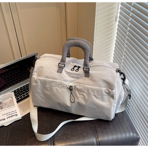 Detail of grey travel bag with checkered pattern, padded handles and drawstring pocket
