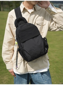 Détail du sac bandoulière en nylon noir avec motif à carreaux et pendentif de tennis