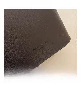 Detail der dunkelbraunen Leder-Oberfläche mit geprägtem Logo auf der Beuteltasche