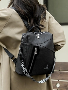 Minimalist black backpack with woven texture and geometric strap shown on a model