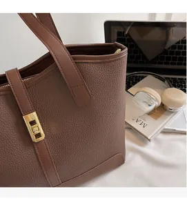 Detailed view of coffee brown pebbled leather texture and golden twist lock on a tote bag