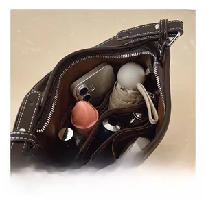 Innenraum der dunkelbraunen Leder-Eimertasche mit geräumigen Fächern und Alltagsgegenständen