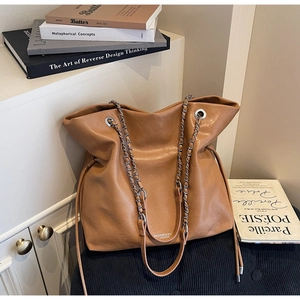 Macro detail of caramel brown tote bag with metal chain strap and drawstring accents