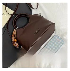 Detailed close-up of dark brown PU leather bucket bag with circular handle and wooden beads