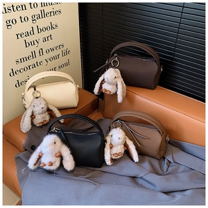Detailed view of stylish leather crossbody bags with cute plush rabbit charms in four colors
