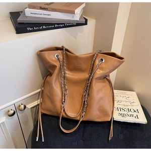 Detail of caramel leather tote bag featuring silver eyelets and side drawstring accents
