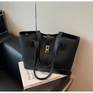 Close-up of black lychee grain leather tote bag with gold metal twist lock detail