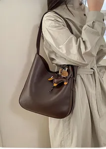 Detail of coffee brown tote bag with leather dachshund charm and logo embossing