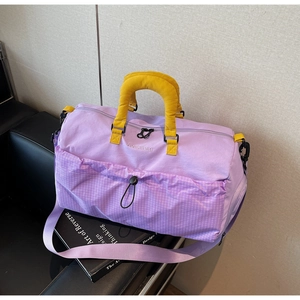 Close-up of lilac travel bag featuring yellow handles and purple grid outer pocket