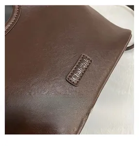 Close-up of retro brown bucket bag showing pebbled leather texture and stitching detail