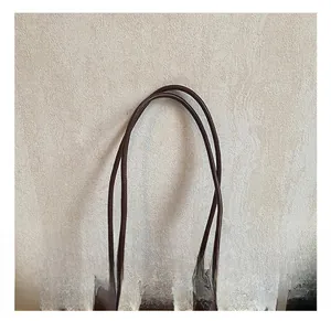 Macro detail of brown leather handle and woven wool texture on a stylish tote bag