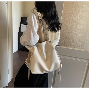 Detail view of large tote bag with silver chain strap and stylish side drawstring