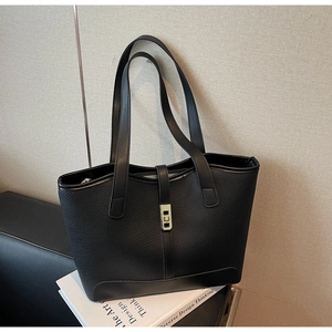 Macro detail of black lychee grain tote bag showing gold lock and premium leather texture