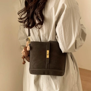 Detail of vintage matte brown bucket bag featuring gold metal lock and cute bear charm