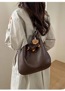 Detail of dark brown leather hobo bag featuring cute dachshund and pastry bag charms