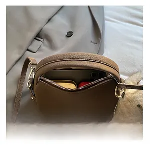 Macro view of brown lychee grain mini bag interior holding a smartphone and essentials