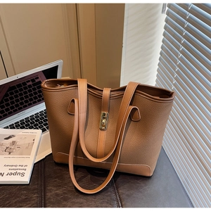 Detailed view of large brown pebble leather tote bag with elegant golden twist lock closure