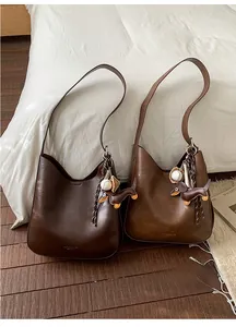 Detail of soft matte PU leather hobo bags in dark brown and caramel with bag charms