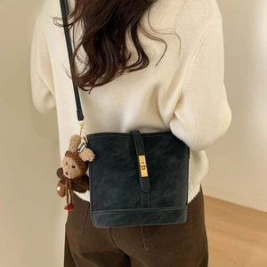 Close-up of retro black bucket bag with golden twist lock and cute brown bear charm