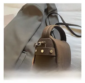 Detailed view of silver rivets and premium lychee texture on dark brown leather bag