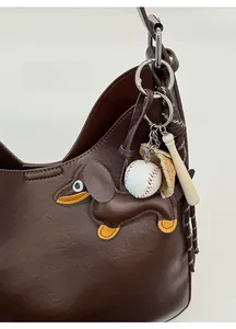Close-up of dachshund leather keychain with baseball charms on a brown tote bag