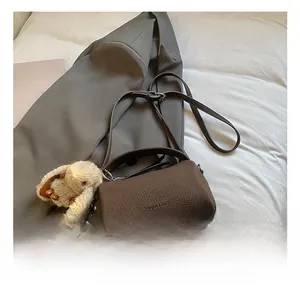 Detail of dark brown lychee leather crossbody bag with cute plush rabbit charm
