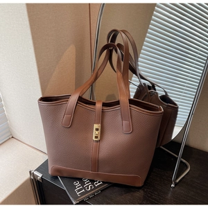 Detail of a brown lychee pattern leather tote bag with a golden metal twist lock closure