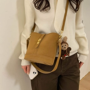 Detail of vintage matte bucket bag in camel with gold twist lock and a cute plush bear
