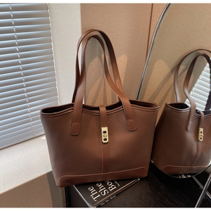 Close-up of litchi texture brown leather tote bag featuring gold metal turn-lock detail