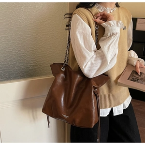 Detail of the high-shine brown tote bag with silver chain straps and side drawstring
