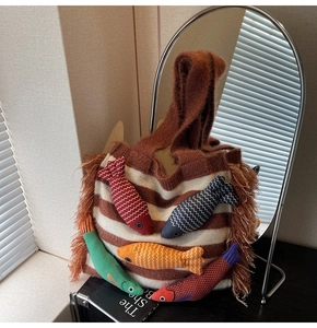Detail of striped knitted tote bag with faux fur trim and five colorful fish charms