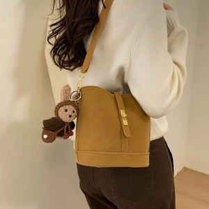 Close-up of yellow bucket bag with golden buckle and cute rabbit doll keychain