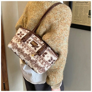Detail of faux fur shoulder bag with leather handles and metallic logo plate