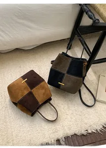Detail of color-block matte leather bucket bags with gold logo and long shoulder straps